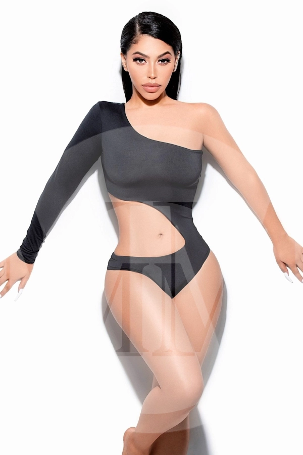 Aliah in a cut out black swimsuit revealing her toned belly and shoulder.