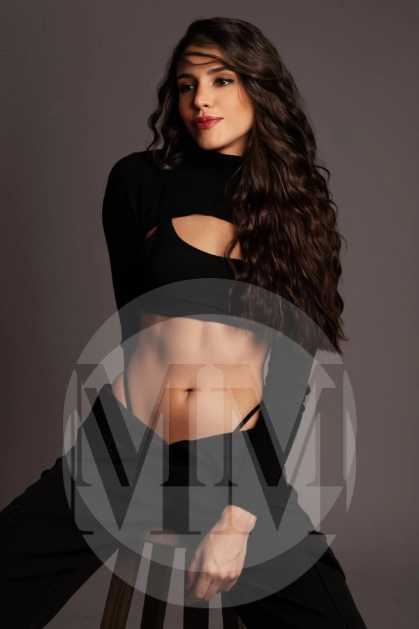 Amal wearing a long sleeved crop top and black bra, toned midsection exposed and thong peeking out.